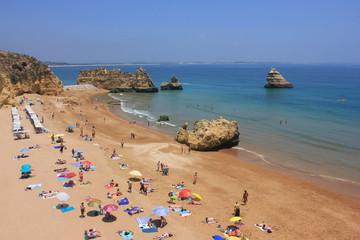 Fototapeta na wymiar Praia Dona Ana Beach in Lagos, Algarve region, south Portugal, Europe. One of the most visited and famous beaches in the world. Summer scene with tourists sunbathing and swimming in Atlantic ocean.