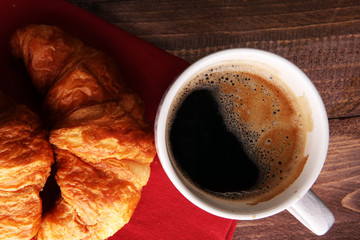 Coffee white cup, croissants on brown wooden background. Breakfast concept