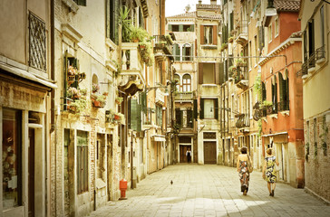 View of the colorful Venetian houses with some visitors walking by in Venice, Italy.