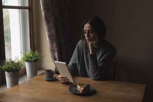 Woman using tablet computer while by window