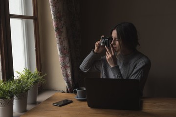 Woman photographing while sitting by window