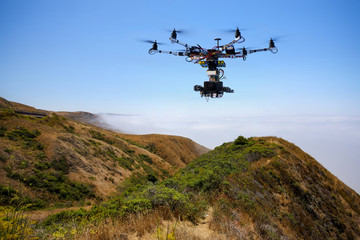 Drone with professional cinema camera flying over Pacific Ocean covered fog and the mountains in California