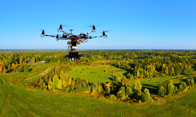 hexacopter with professional cinema camera flying over a autumn park in fall colors under morning light with deep long shadows