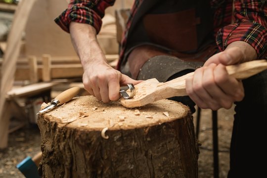 Mid section of carpenter making wooden spoon