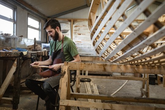 Attentive carpenter making wooden spoon