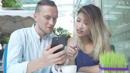 Fototapeta premium Multicultural couple watch movie together on smartphone