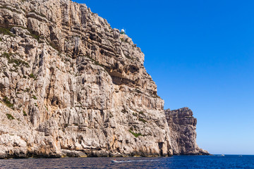 Sardinia, Italy. A picturesque rocky coast and a pleasure boat near cape Capo Caccia