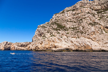 Fototapeta na wymiar Sardinia, Italy. A picturesque rocky coast near cape Capo Caccia and a boat