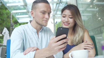 Mixed race couple looking photos together on smartphone