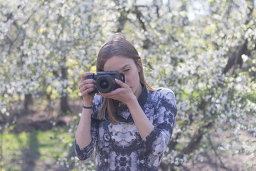woman photographer with camera in spring park 