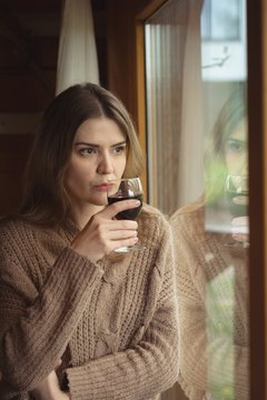 Thoughtful woman having glass of wine