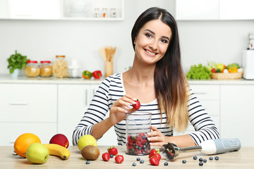Beautiful young woman cooking smoothie in blender