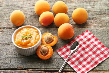 Apricot jam in bowl with spoon on grey wooden table