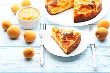 Slice of apricot pie with fruits on blue wooden table