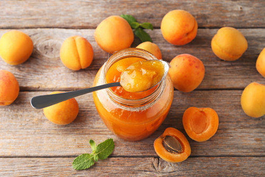 Apricot jam in glass jar on grey wooden table
