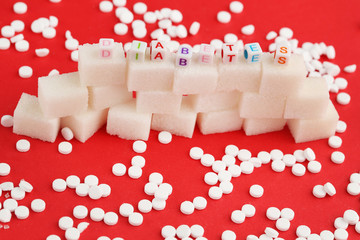 Sweetener tablets and sugar cubes with inscription Diabetes on red background