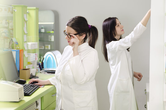 Two young adult woman working in pharmacy 