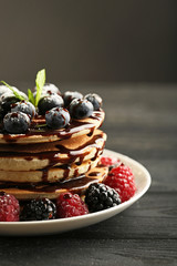 Tasty pancakes with berries on black wooden table