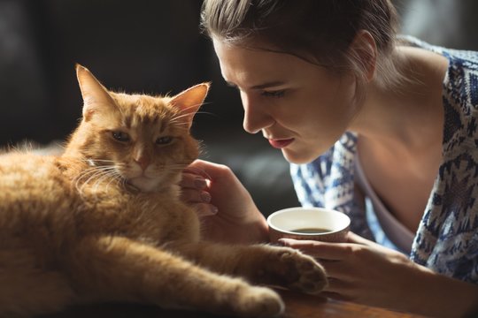 Woman Petting Cat While Having Coffee