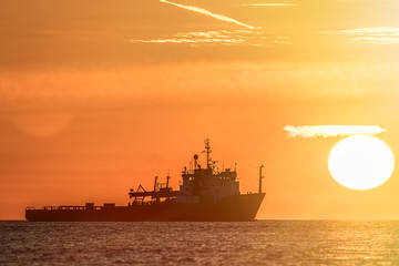 Travel destination. Sun haze over a tropical ocean at sunrise. Fishing boat silhouette infront of a glowing sun.