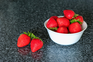 Small white bowl filled with red strawberries.