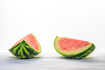 Two pieces of a watermelon on white wooden table on white background background front view. Blank minimalistic background