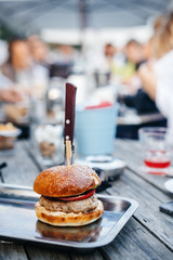 Juicy burger with a knife on a tray in the company.