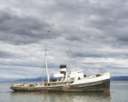 Wrecked abandoned ship near Ushuaia. Red airplane over it. Tierra del Fuego province in Argentina. Patagonia.