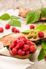 Raspberry in a bowl, berries and leaves on a shabby  wood