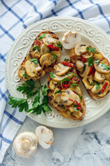 Crostini with mushrooms and onions on a white plate.