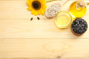 Sunflower oil in glass jug , seeds and flower on light wooden background. top view with copy space