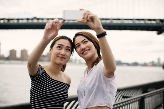 Women taking a selfie with Brooklyn bridge background 