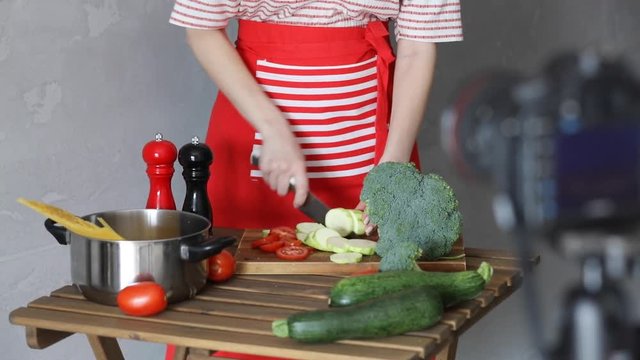 Young caucasian blogger woman cooking food at camera for Video-sharing website. Home location at kitchen