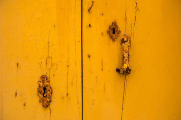 Rusty vintage keyhole on a yellow door