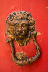 Lion head door knockers on a red door