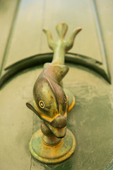 Fish shaped knocker on a green wooden door.