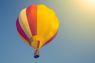 Fototapeta premium Colorful air balloon in a blue sky in sunlight. Toned