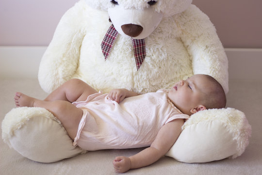 Beb&eacute; durmiendo sobre el regazo de un oso de peluche