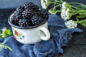 Ripe blackberries in a cup on a dark background