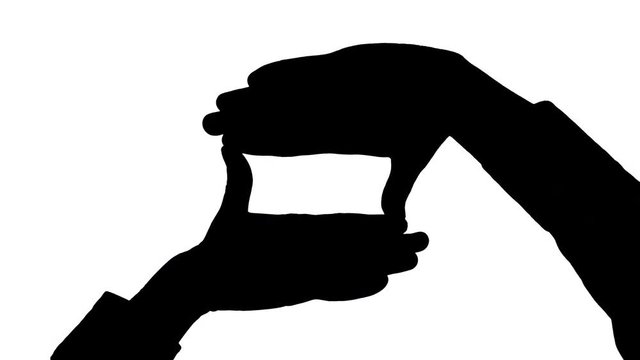 Moving male hands frame gesture Black silhouette of two male hands holding fingers in a frame gesture appears moving from the bottom of the frame against white background
