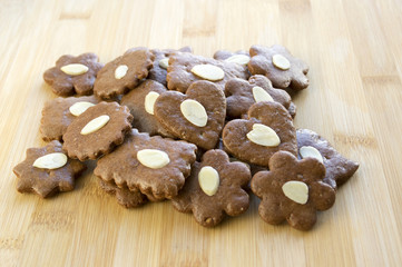 Brown moravian dark gingerbreads with sliced almonds on wooden table, christmas cookies, Variety of shapes