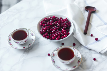 cranberry (cowberry) on marble background with tea