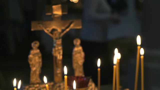 Candlestick with burning candles for the repose of and a cross of gold colors in the temple. Close up