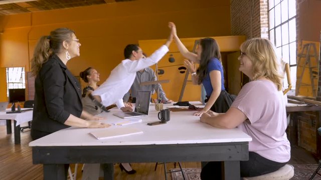 Group of young creative professionals high five celebrating business success