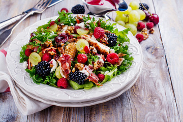 Delicious summer salad with mix of berries, nuts, feta chees, bacon and raspberry sauce on vintage...