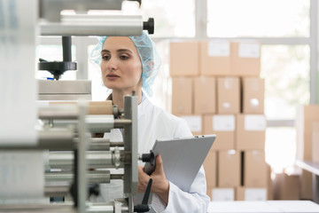 Female manufacturing supervisor looking worried while checking equipment and production during...
