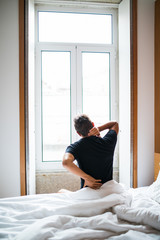 Man feeling back ache in the bed after sleeping in the morning