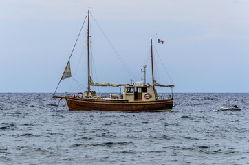 Fototapeta premium Traditional sailboat with Italian flag and its lifeboat