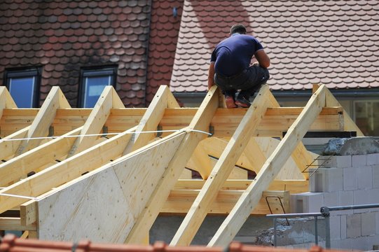 Zimmermann beim Messen auf dem Dachstuhl eines neu zu errichtenden Wohngebäudes in der Altstadt