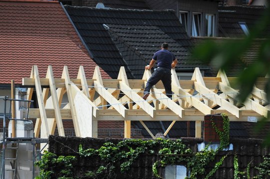 Zimmermann beim Messen auf dem Dachstuhl eines neu zu errichtenden Wohngebäudes in der Altstadt